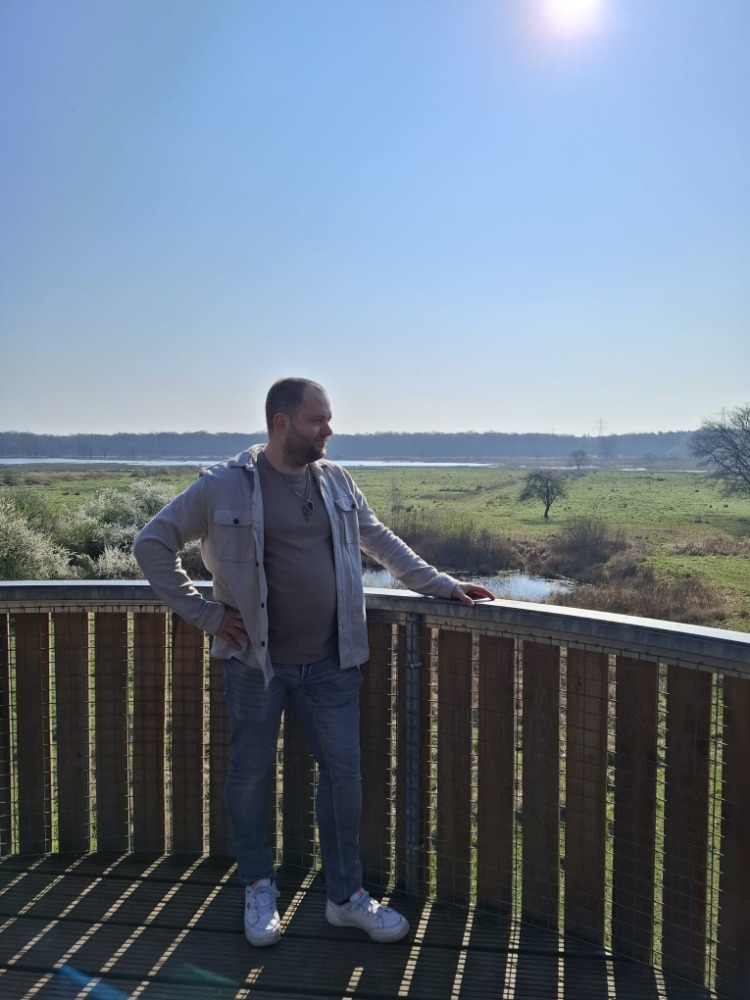 Erik staand op een uitkijkplatform met de Brabantse polder achter zich